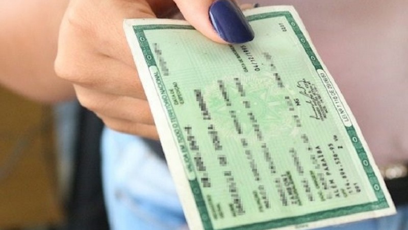 Imagem mostra uma mão segurando uma carteira de identidade