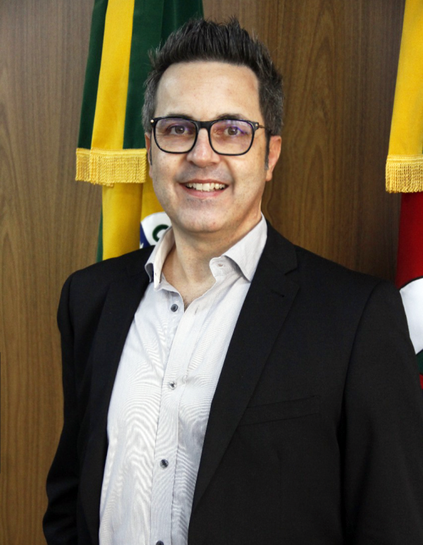 O diretor-geral do EDP, Hiparcio Stoffel, aparece em pé, diante das bandeiras do Brasil e do Rio Grande do Sul