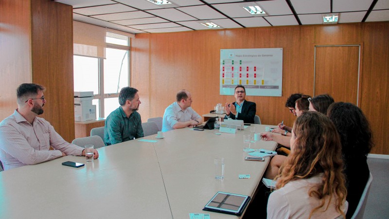 Representantes do governo do Estado e dos EUA sentados em torno de uma mesa de reuniões