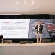 Stoffel em pé, sobre um palco, apresentando o RS Digital, acompanhado pelos titulares da SPGG