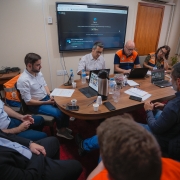 Grupo de pessoas, lideradas pelo vice-governador, trabalha em torno de uma mesa com computadores